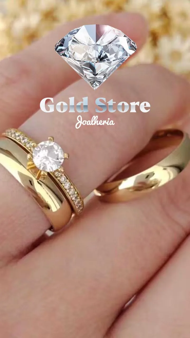 Solitário de ouro com brilhante e par de alianças na mão, com o logo Gold Store Joalheria